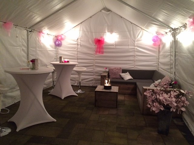 Partytent van 4 × 6 meter tegen een woning, met statafels, barkrukken, verlichting en verwarming.