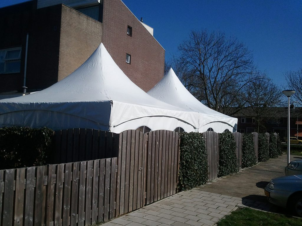Verjaardag in de tuin met twee pagodetenten, stoelen, statafels en een vloer op het gras.