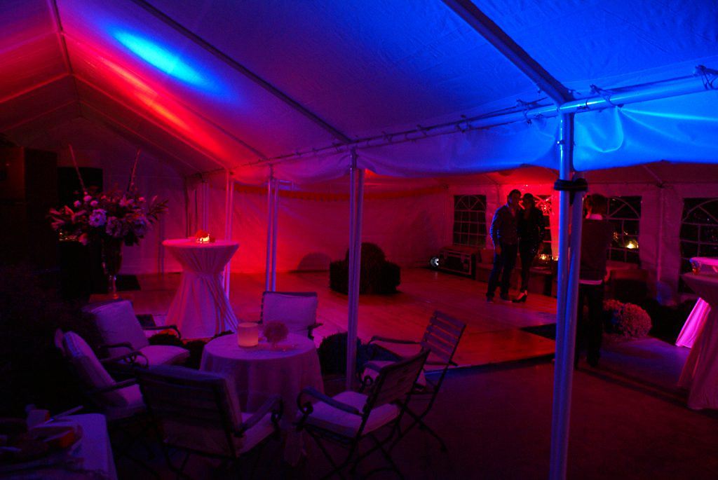 Twee gekoppelde tenten vormen een overkapping van 10 × 12 meter, met houten vloer en sfeerverlichting.