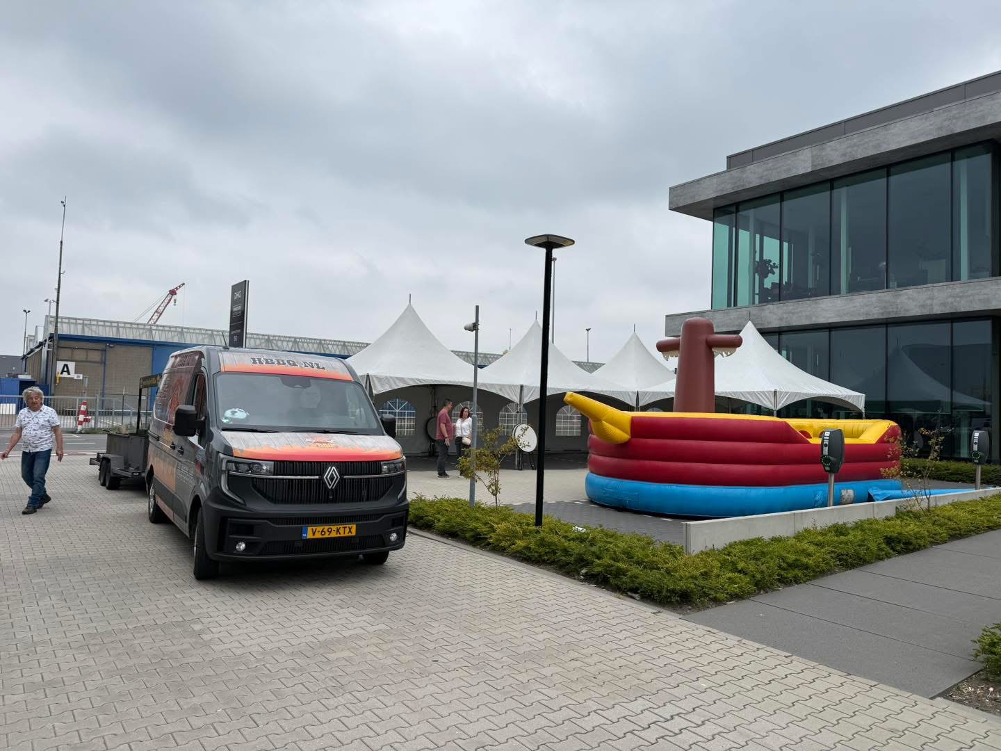 Bestelbus bij een evenement met witte pagodetenten en een piratenschip-springkussen