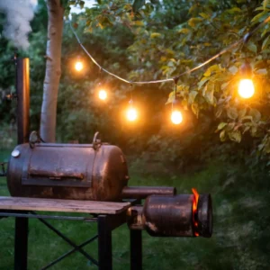 Sfeerverlichting met witte lampen aan een zwart snoer boven een barbecue