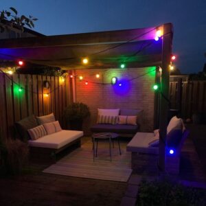 Gekleurde sfeerverlichting boven een gezellige zithoek onder een houten overkapping